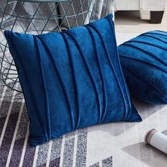 two blue pillows sitting on top of a rug