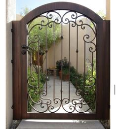 an iron gate with wooden posts and metal bars on the top, in front of a house