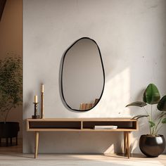 an oval mirror hangs on the wall above a wooden table with a potted plant next to it