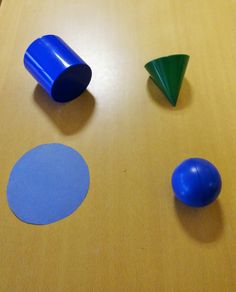 three different colored plastic objects sitting on top of a wooden table next to each other