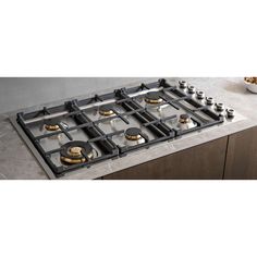 a stove top with four burners and two plates on the counter next to it