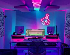 a computer desk topped with lots of monitors and speakers in a room filled with neon lights