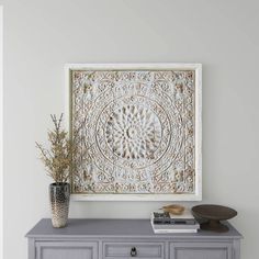 a gray dresser with an ornate design on the top and bottom, next to a white wall