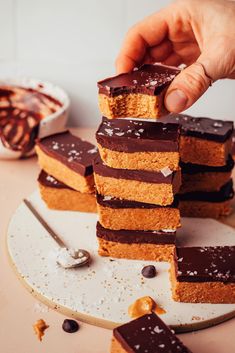 a person picking up some kind of dessert from a white plate with chocolate on it