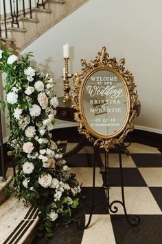 a welcome sign with flowers and a candle in front of it on a checkered floor