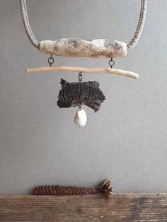 a piece of driftwood is hanging from a branch with a white bead on it