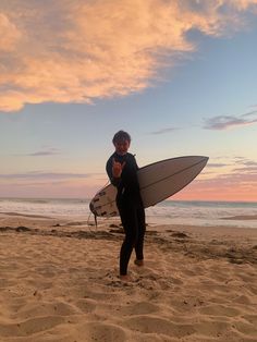 a man holding a surfboard on top of a sandy beach