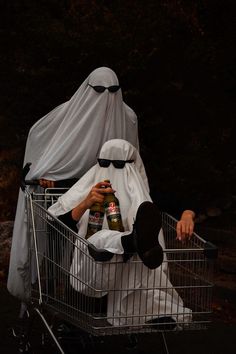 a person sitting in a shopping cart with a covering on their head and holding a bottle