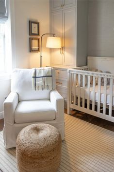 a baby's room with a crib, chair and ottoman