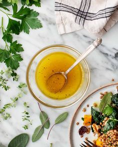 a white plate topped with salad next to a glass bowl filled with greens and dressing