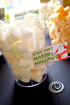 some marshmallows are in a glass on a table with a sign that says stay puft marshmallow