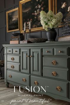 an antique dresser painted in green with gold handles and knobs, has flowers on top