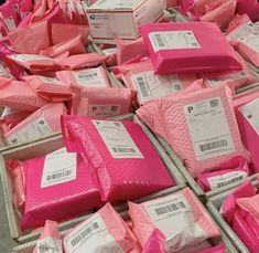 many pink packages are stacked on top of each other in bins with price tags