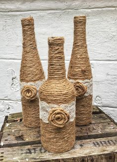 three burlap vases with twine wrapped around them on a wooden table