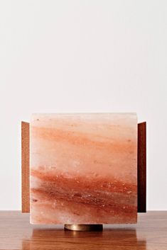 an orange marble block sitting on top of a wooden table next to a white wall