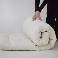 a person is holding the back of an unmade comforter in front of a white wall