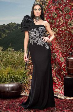 Standout in a couture design that speaks of artistry in this Tadashi Shoji BRX20628L creation. Draped on one shoulder with an oversized rosette accent, this inspired piece flourishes an asymmetrical neckline with its dominant short sleeve. Embroidered florals contrast the fitted bodice. The sheath skirt streams elegantly down to a sweeping finish. Celebrate that inner diva in you in this Tadashi Shoji masterpiece. #eveningdresses #promdresses #stunningdresses Flower Gown, Couture Design, Tadashi Shoji Dresses, Embroidered Bodice, One Shoulder Gown, Corded Lace