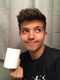 a young man holding a roll of toilet paper in his right hand and smiling at the camera