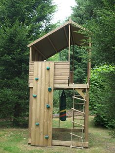 a wooden structure with climbing ropes on the side and a green towel hanging from it