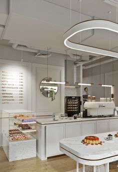 the interior of a bakery with white counter tops and marble tables, along with various pastries on display