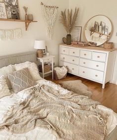 a white bed sitting in a bedroom next to a dresser and mirror on top of a wooden floor