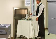 a man standing in front of a table with a tea kettle on top of it