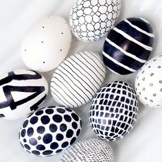 an assortment of painted easter eggs on a white surface with black and white designs around them