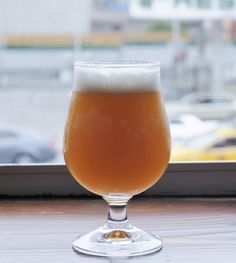 a glass of beer sitting on top of a window sill