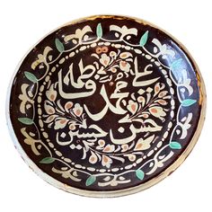 an ornately decorated bowl with arabic writing on the bottom and green leaves in the middle