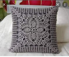 a gray crocheted pillow sitting on top of a bed