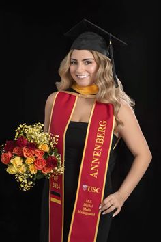 a woman wearing a graduation gown and holding flowers