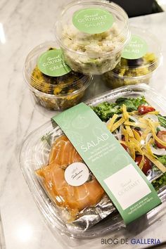 three plastic containers filled with salads on top of a marble countertop next to each other