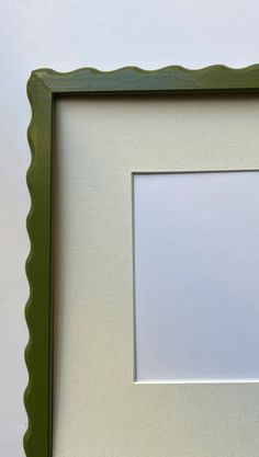 a white and green frame with a small square in the middle on a table next to a wall