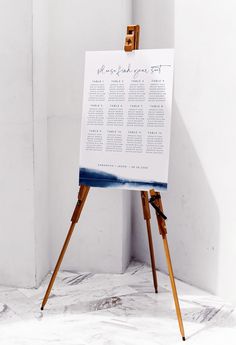 an easel with a wedding seating chart on it in front of a white wall