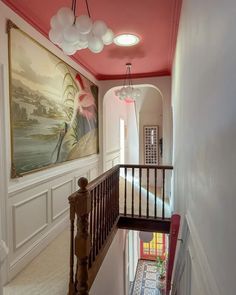 the hallway is painted in pink and white with an art work on the wall behind it