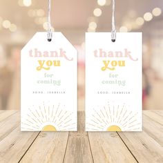 two tags with thank you for coming out of the box on top of a wooden table