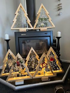 a group of christmas trees sitting on top of a table next to a fire place