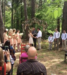 a group of people standing around each other in the woods with one man holding a camera