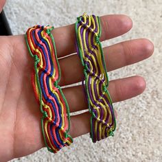 two colorful bracelets are held in someone's hand