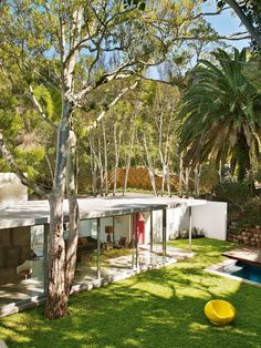 the house is surrounded by trees and grass, with a yellow object in the foreground