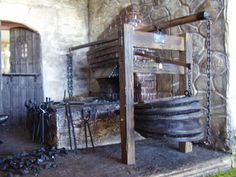 an old fashioned fire place with chains hanging from it's sides and logs on the ground