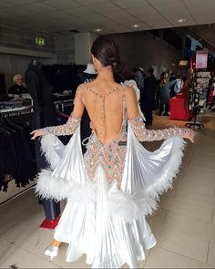 a woman in a white dress with feathers on it's back and her arms spread out