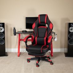 a gaming chair sitting in front of two speakers and a desk with a monitor on it