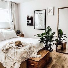 a bedroom with a bed, mirror and plants on the floor in front of it