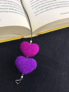 two purple and pink heart shaped pom - poms are on top of an open book