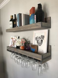 a shelf with wine glasses and books on it next to a wall mounted wine glass holder