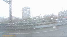 rain is falling down on the windshield of a car as it travels through an urban area