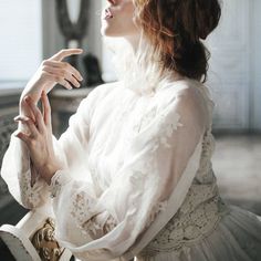 a woman in white dress sitting down with her hands together