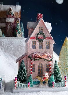 a christmas scene with a pink house in the snow