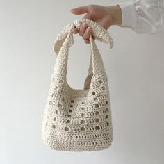 a crocheted purse being held by a woman's hand with white background